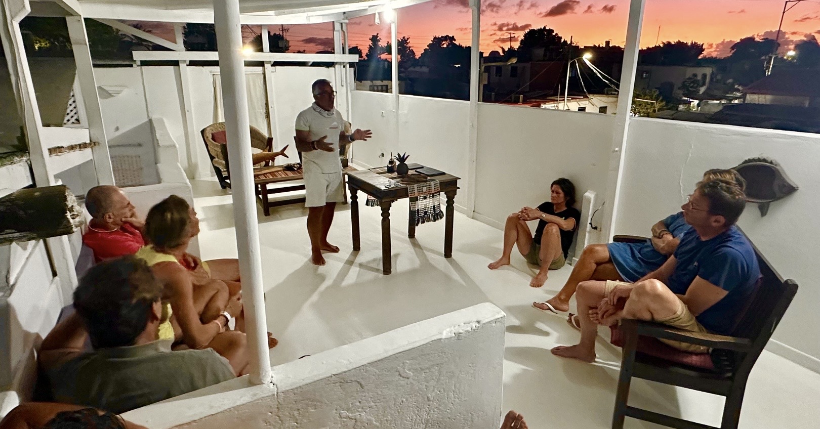 Gruppo di persone conversa su terrazza al tramonto